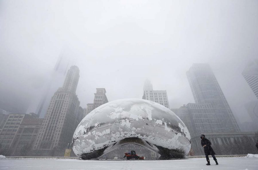 A woman walks by the Cloud Gate Sculpture, known as "The Bean", as a snow plow clears the area during a snowstorm in Chicago March 5, 2013. A deadly late winter storm dumped heavy snow on the Midwestern United States on Tuesday, contributing to numerous highway crashes and flight cancellations as it moved east toward the Ohio Valley and the mid-Atlantic states.  REUTERS/Jim Young  (UNITED STATES - Tags: ENVIRONMENT SOCIETY) ORG XMIT: CHI905