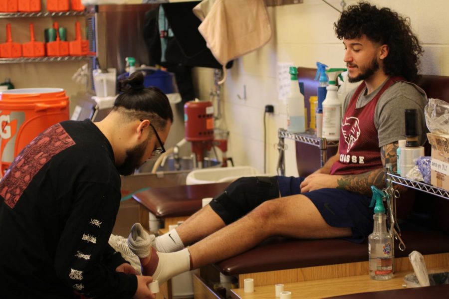 Amir Cavic, a mens lacrosse and football player, gets his foot wrapped by Jose Alcantar, a temporary trainer at CUC