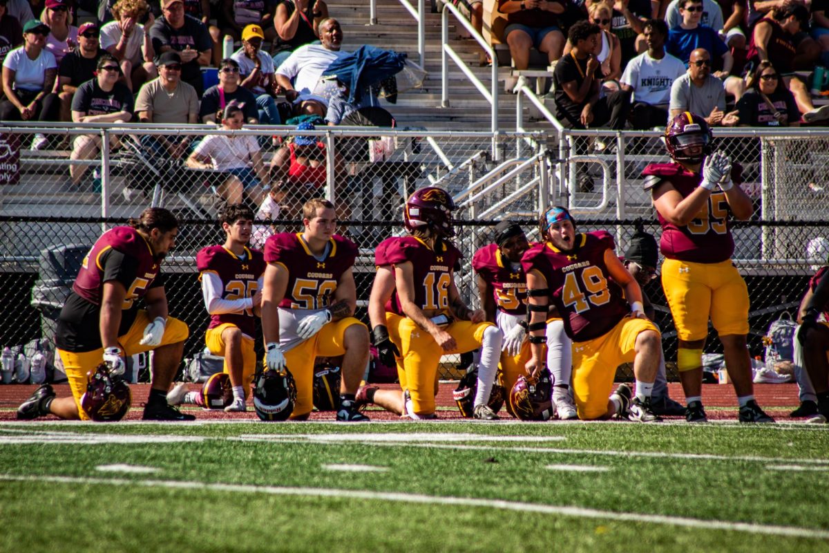 Football players kneel and clap for injured player during the Homecoming 2025 game October 4th