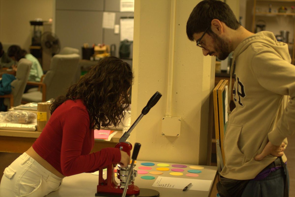 Junior Anastashia Balderrama shows Senior Nathan Goman how to use the button maker at an Art Club event in the Makerspace on October 22.