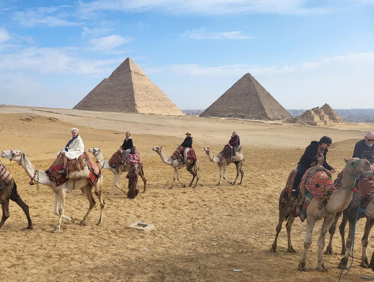 Tourists take a camel ride in front of the Great Pyramids at Giza.